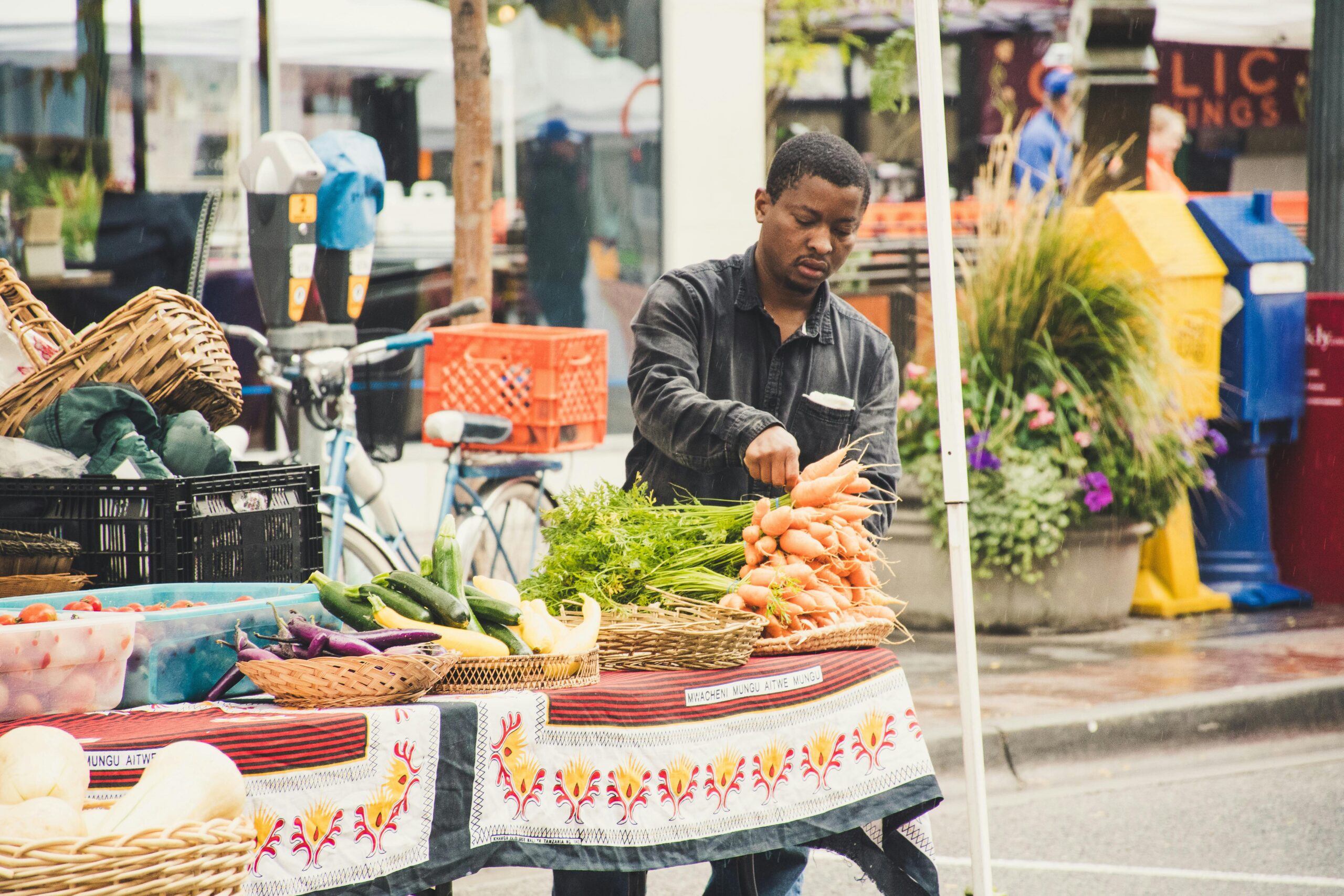 Man arranging fresh vegetables at an outdoor street market stall.