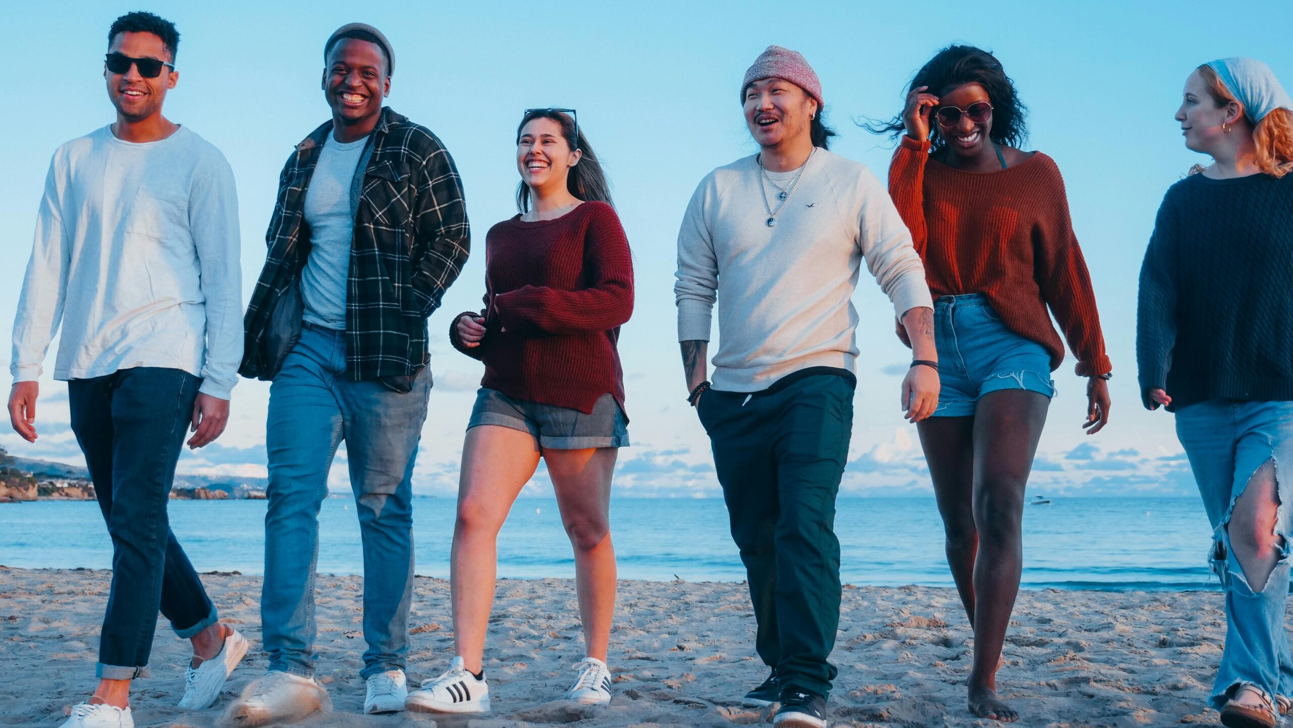 A group of friends enjoys a leisurely walk on the beach at sunset, embodying happiness and togetherness.