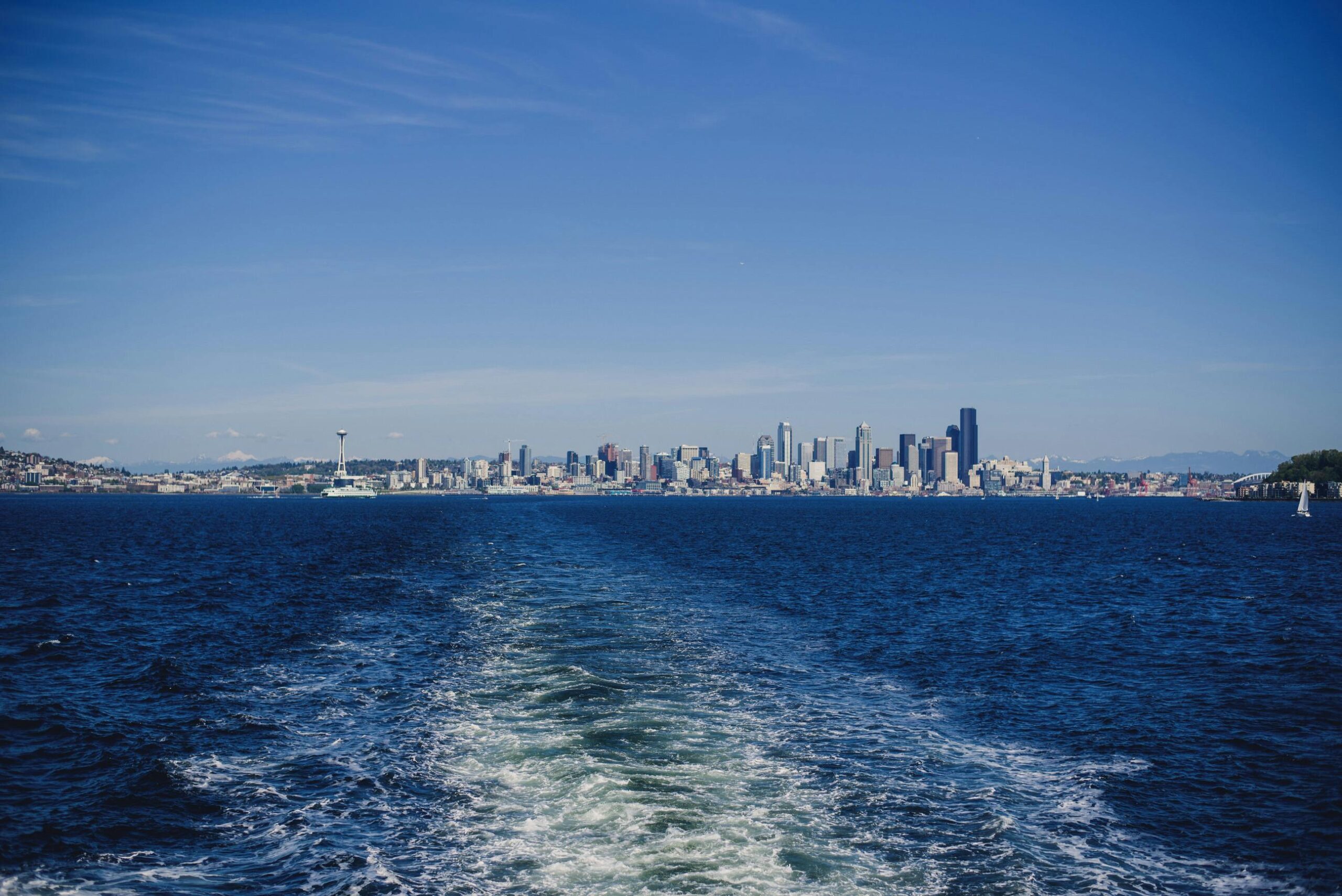 View of Seattle skyline across Puget Sound from a ferry on a sunny day.