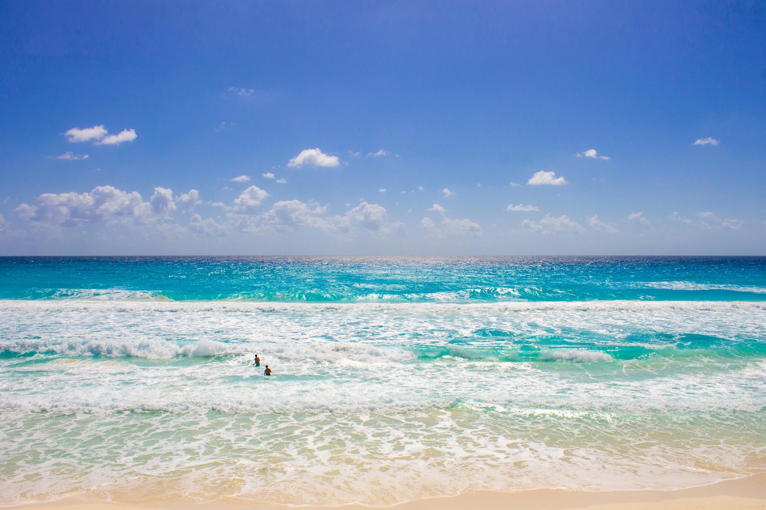 Vibrant beach scene in Cancún with clear blue water and sunny skies.